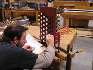 Technician Sean Estanek, laying out stop names on draw jamb of pipe organ console