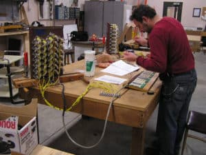 Voicer/Technician Sean Estanek Wiring pipe organ console draw knobs to circuit cards on solid state plane preparing these for testing and installation on site.