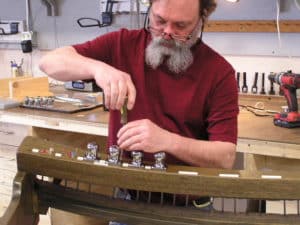 Technician reinstalling toe pistons on pedal board of pipe organ