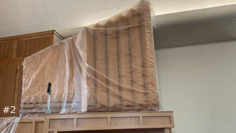 Close-up view of a graduated row of tall wooden organ pipes enclosed under clear protective plastic sheeting on an elevated platform