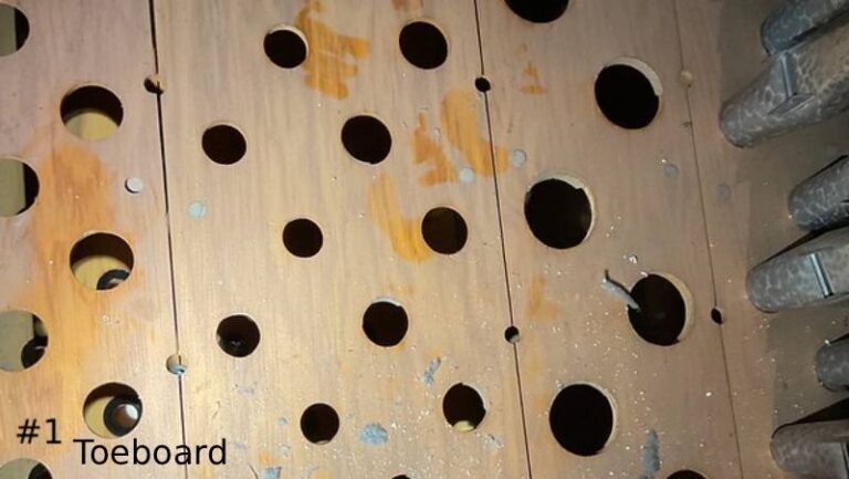 Top-down close-up of a dusty wooden pipe organ toeboard surface