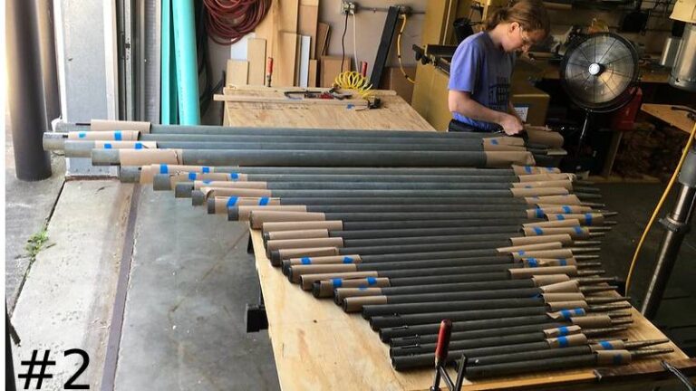 A large collection of metal organ pipes laid out symmetrically by size.