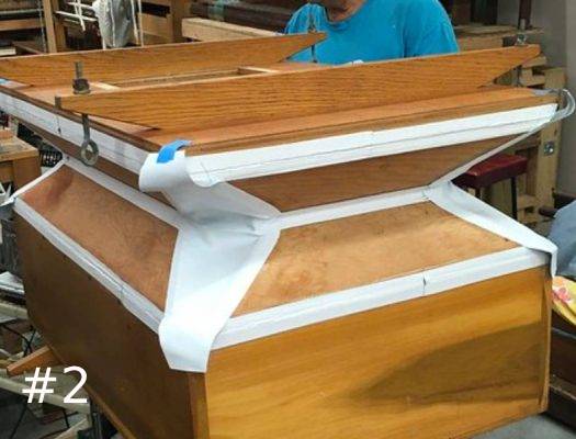 A newly restored wooden pipe organ reservoir bellows featuring fresh white leather sealing strips and corners along its expanding folds.