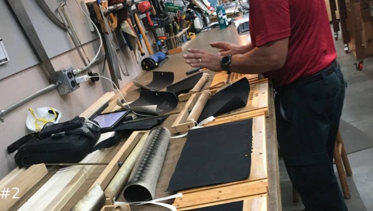 An organ technician replacing rubber cloth materials in wooden frames in a workshop.